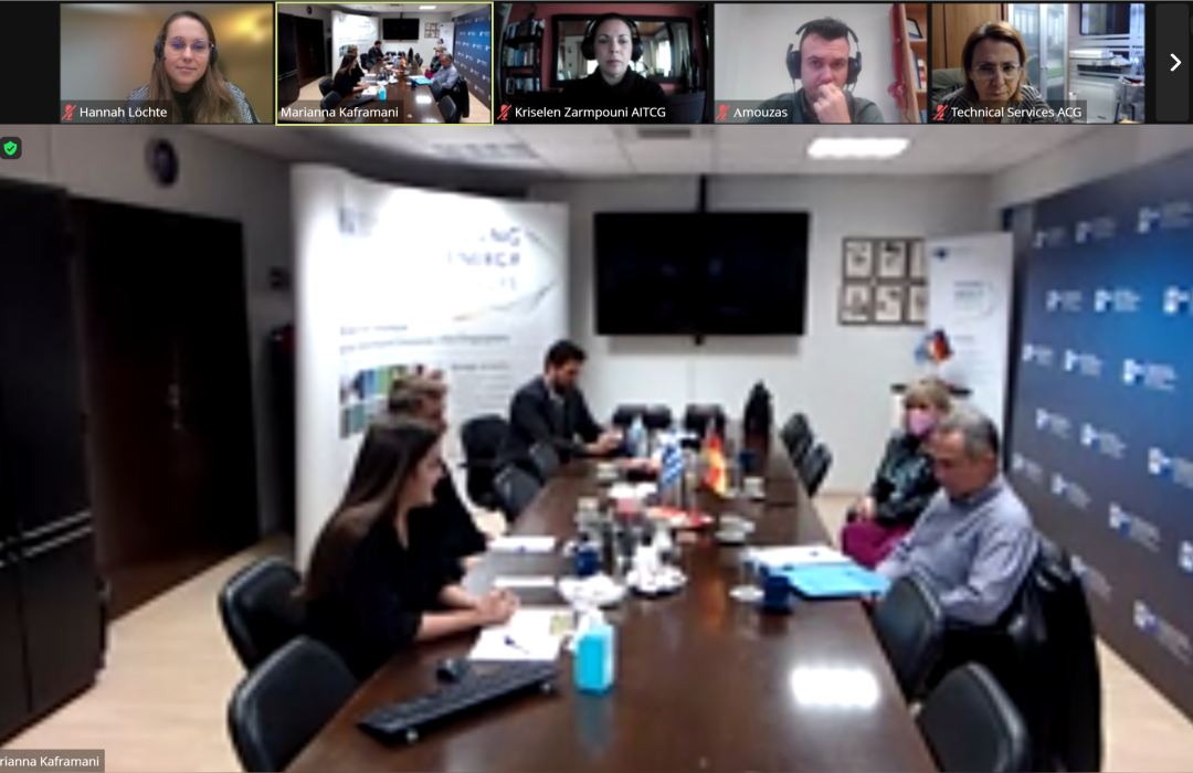 A screenshot of a Zoom, in the spotlight of the call is a conference room with five people