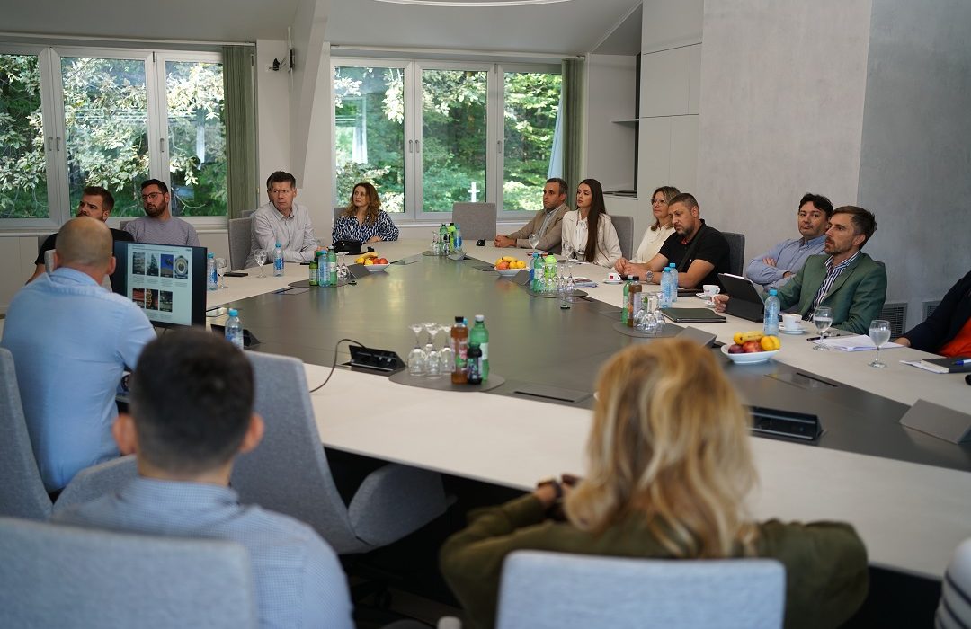 A group of 14 people in a meeting room listening to a presentation