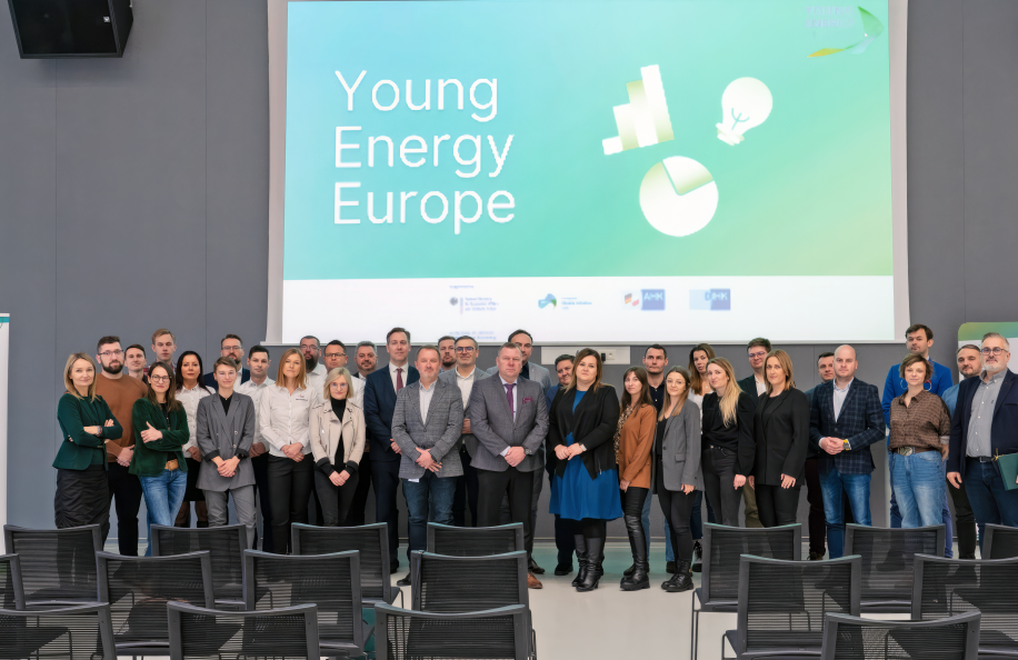 A group of about 35 people, officially dressed, stand in front of a screen that reads "Young Energy Europe"