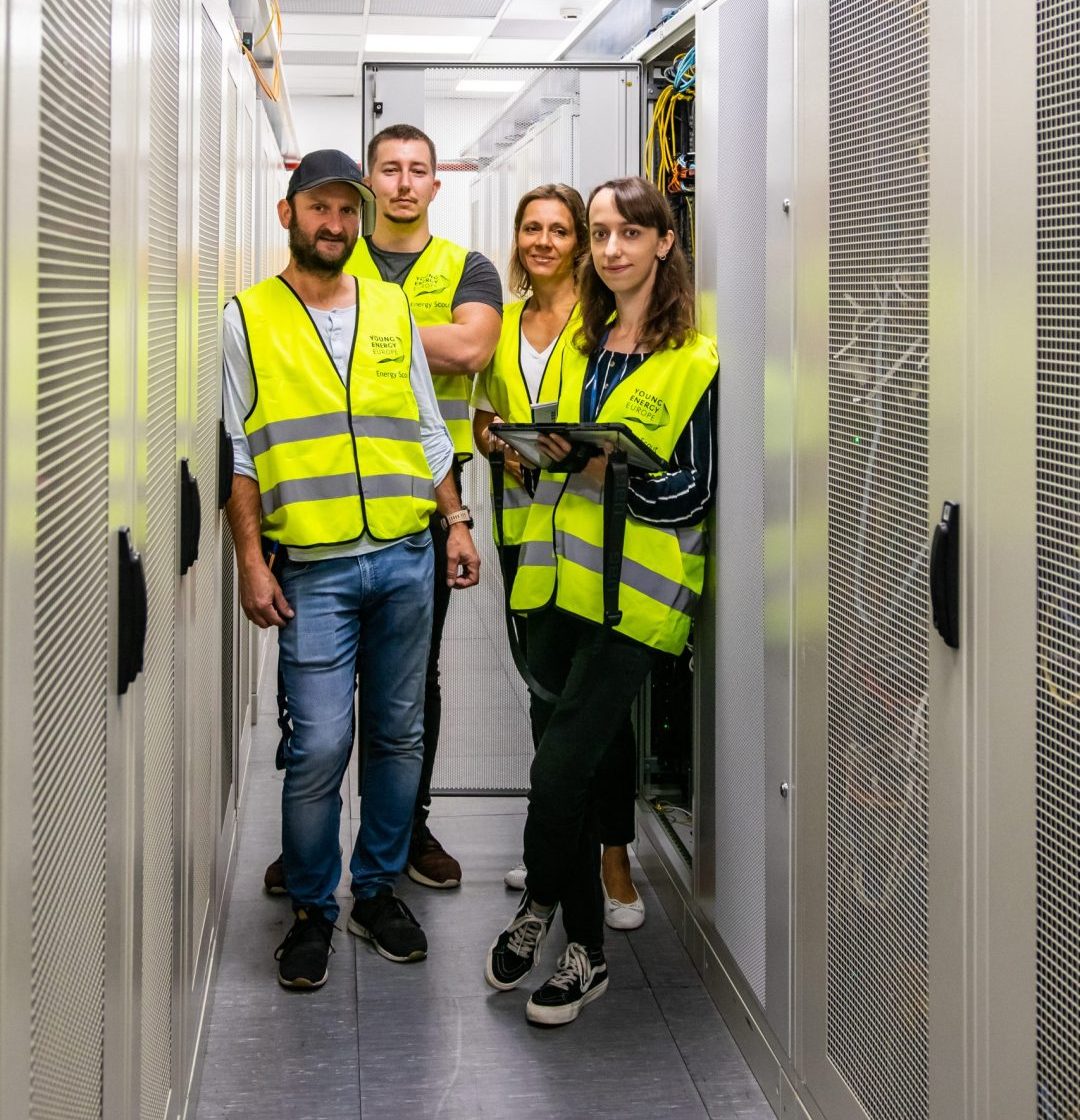 Two men and a woman in yellow Young Energy Europe vests stand next to each other in a data center