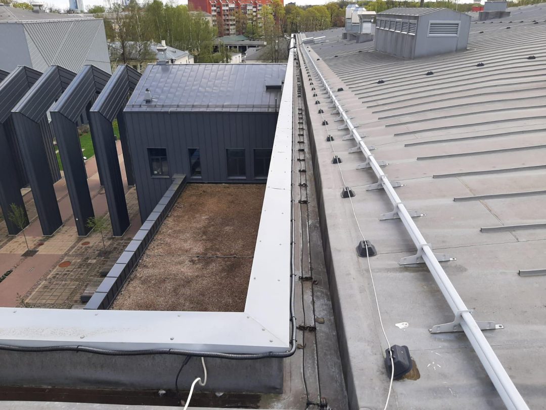 Dächer zweier angrenzender Gebäude; eines mit Flachdach und Kies, das andere mit geneigtem Metalldach und Lüftungseinheiten.